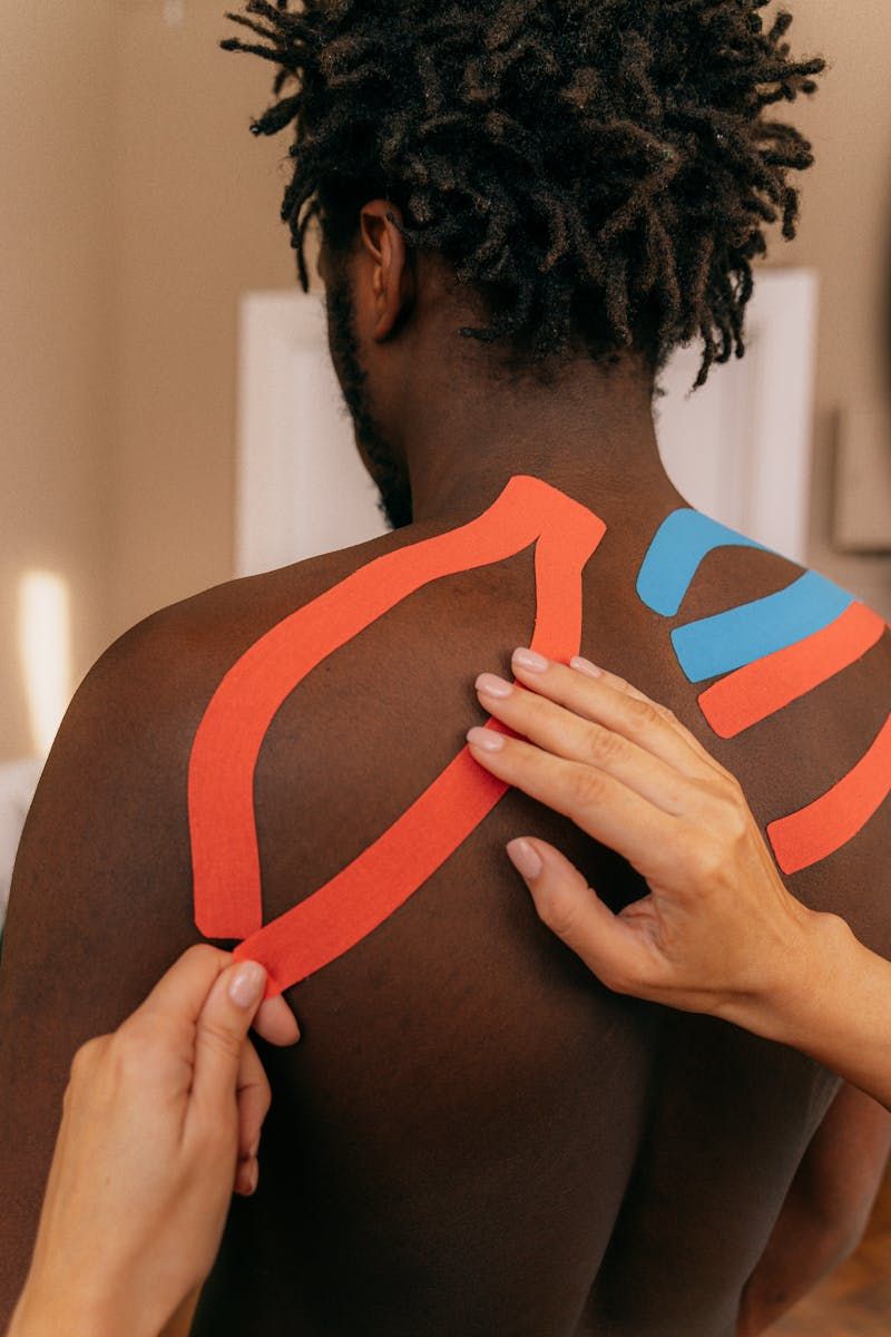 Applying KT tape around man's upper body to help posture
